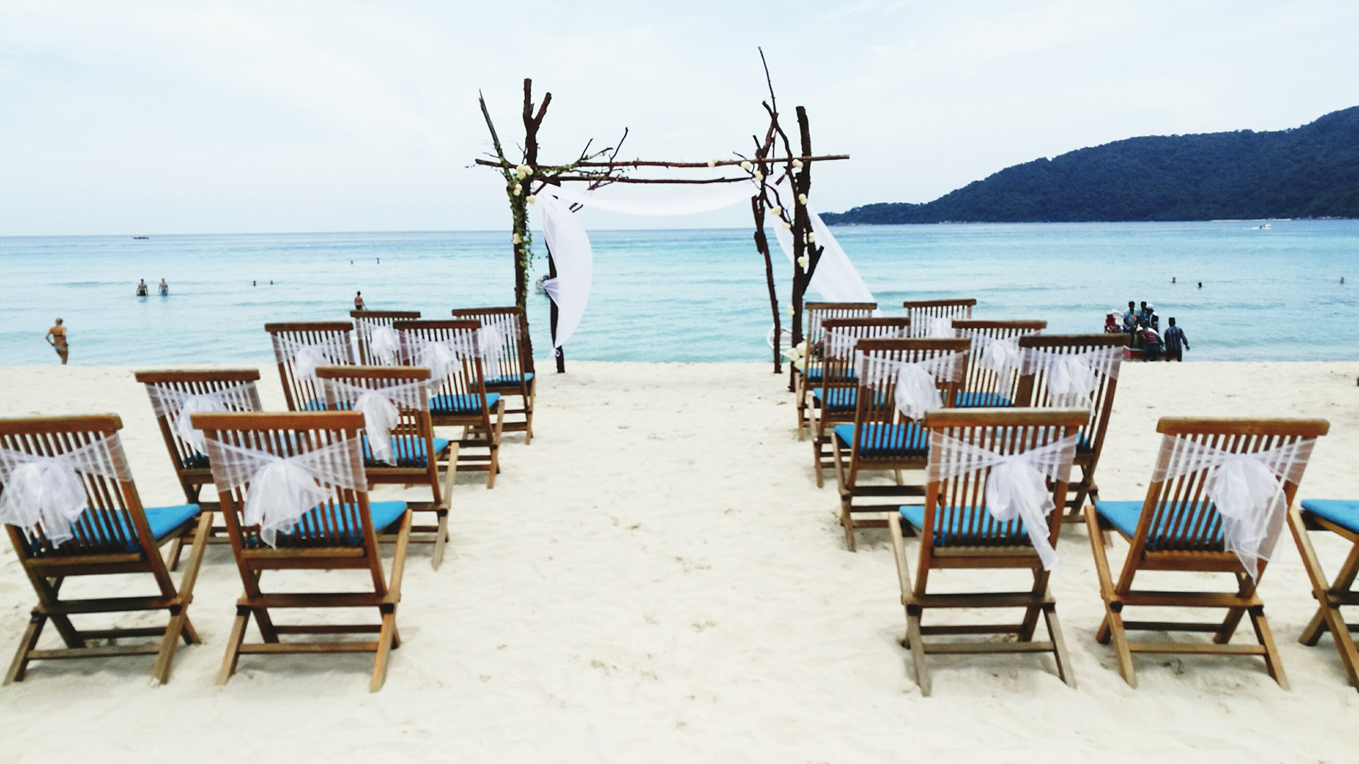 Empty Chairs Arranged At Sandy Beach For Wedding Ceremony